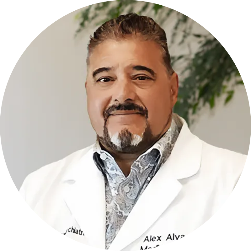 Dr-Alejandro-Alva-1 - Pacific Coast Mental Health Smiling man in a white lab coat facing the camera.
