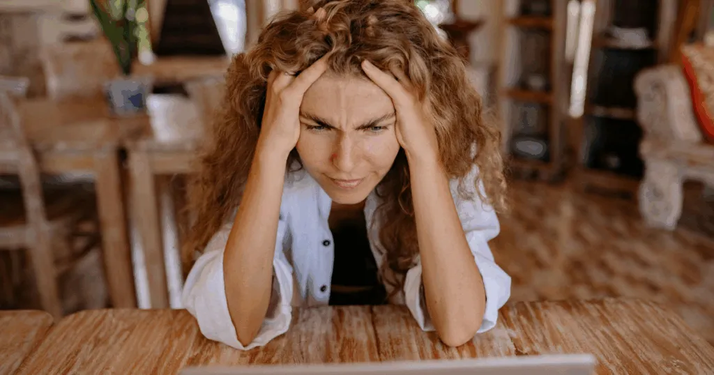 Woman experiencing Sertraline withdrawal symptoms, holding her head in distress. Mental health and medication management.
