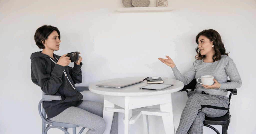 Suboxone withdrawal support: Two women discussing challenges over coffee near a laptop, aiding recovery.