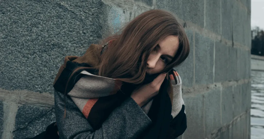 Woman wrapped in scarf coping with impulse control disorders, harnessing inner strength, mental health concept, looking down.
